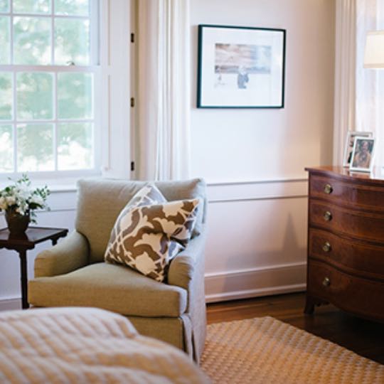 chair with pillow by window in bedroom