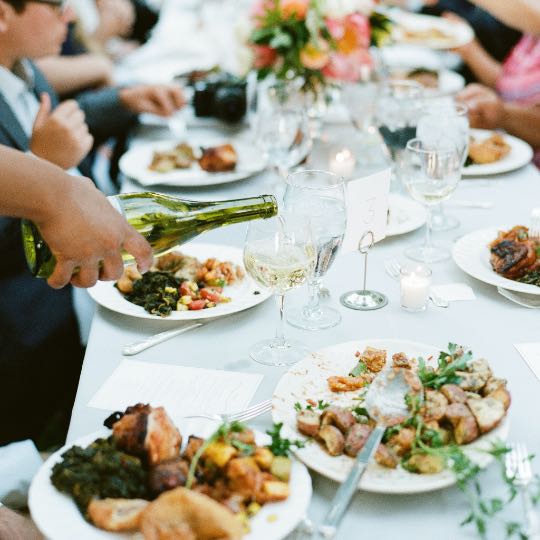 table with plates of food and wine being poured into a glass